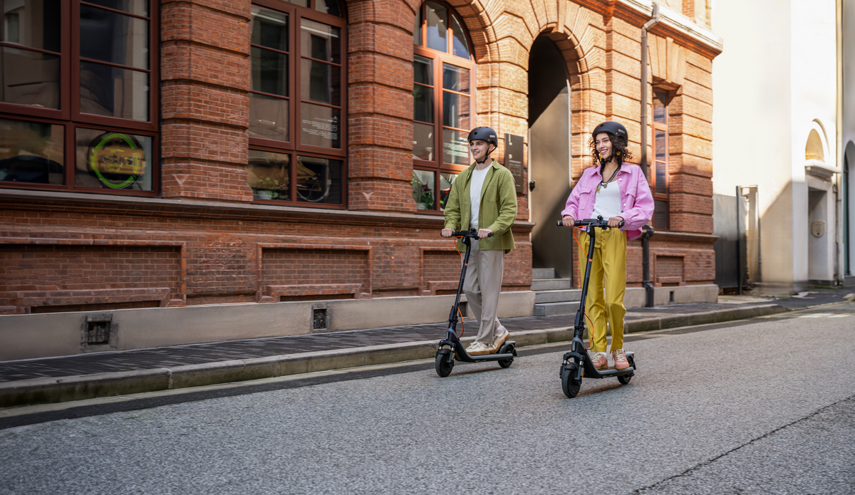 Deux personnes casquées roulant en trottinette électrique Segway Ninebot sur la chaussée en ville
